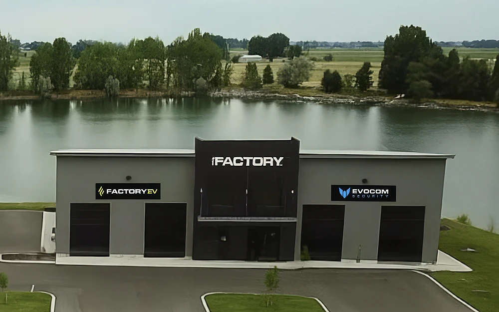 A completed commercial building beside a pond: a dark entry tower between two shop bays